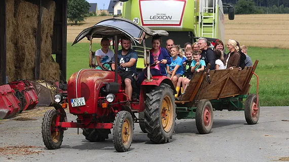 alter Trecker Marke Porsche mit Anhänger voller Gäste