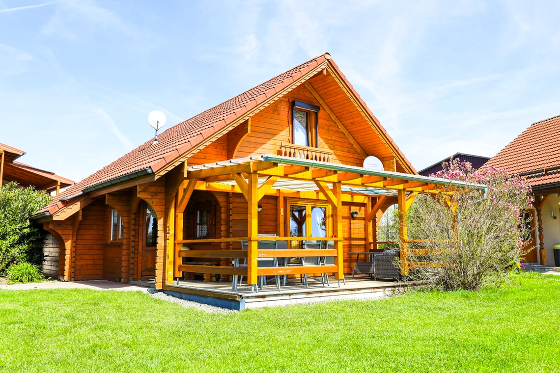 Blick über grünem Rasen auf Blockhaus