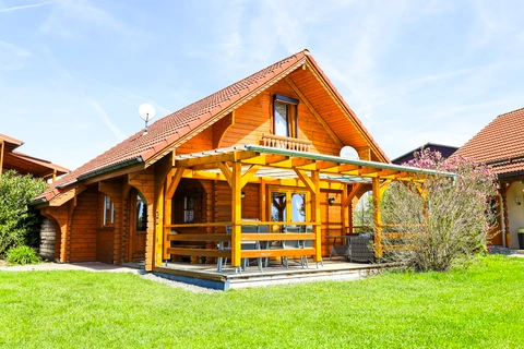 Blick über grünem Rasen auf Blockhaus