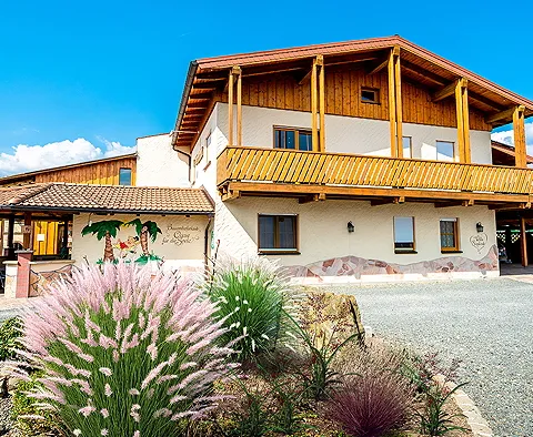 Ansicht auf Erdgeschoss und Holz-Balkon des Massivhauses namens Villa Sieglinde