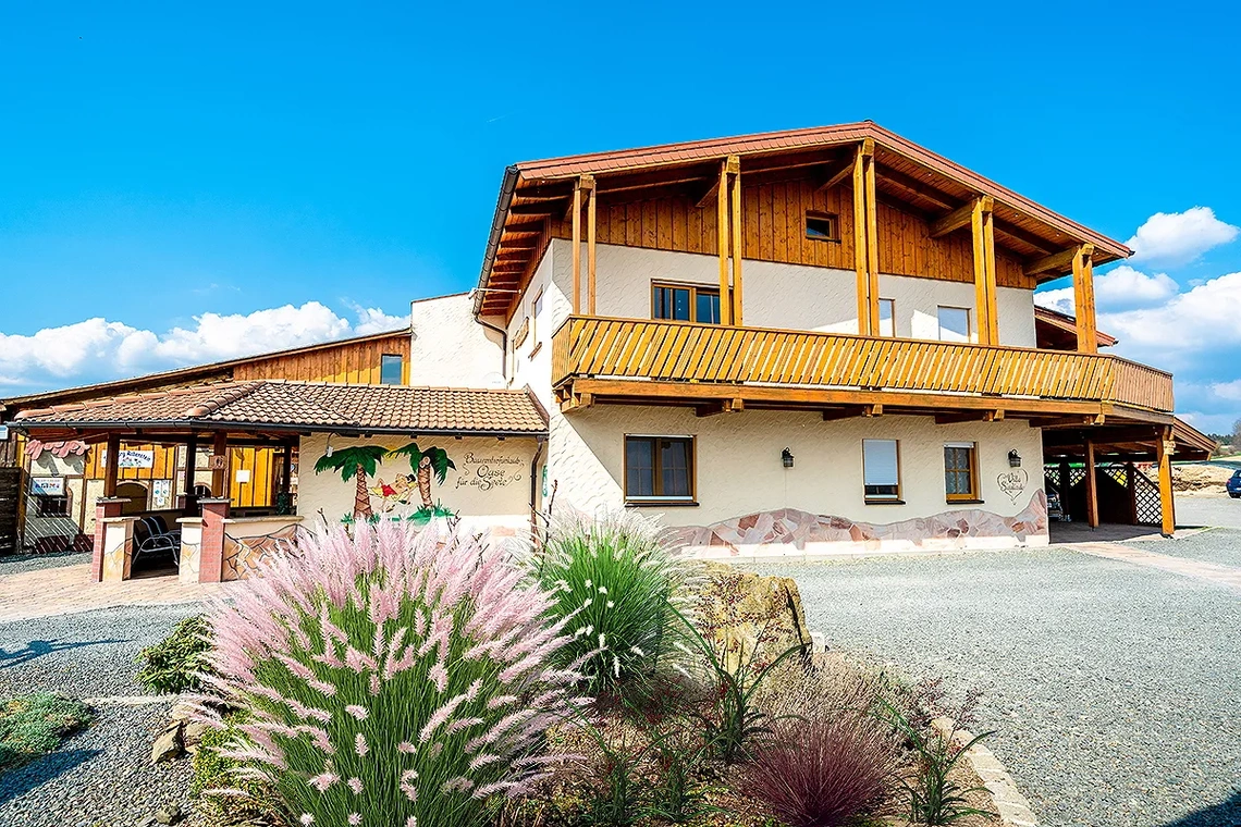 Ansicht auf Erdgeschoss und Holz-Balkon des Massivhauses namens Villa Sieglinde
